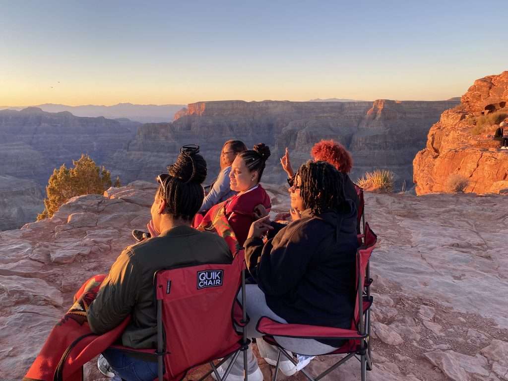 friends sitting in red foldable chairs on canyon edge