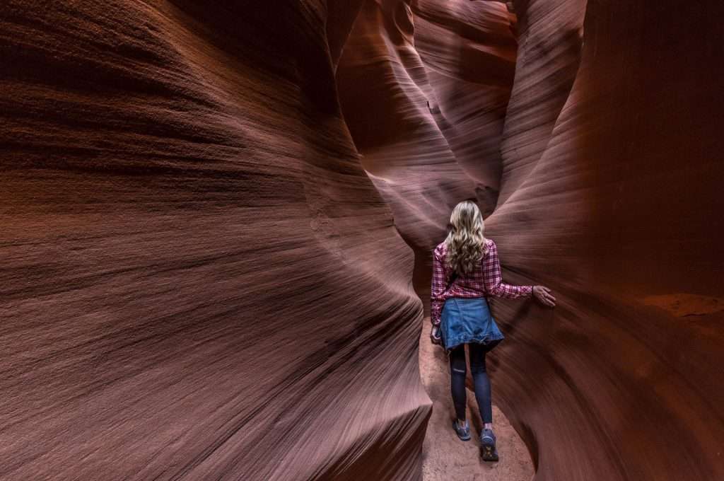 woman running hand along canyon wall in Antelope Canyon