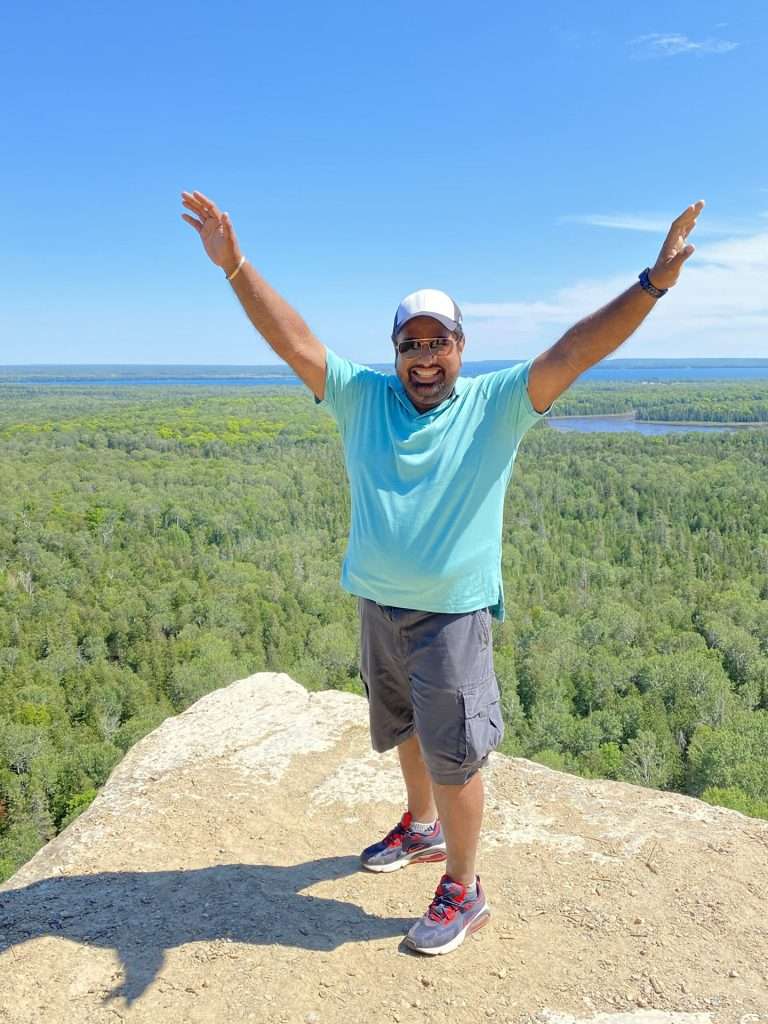 man with arms outstretched in front of valley of trees