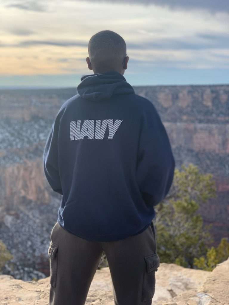 person in black hoodie looking over canyons