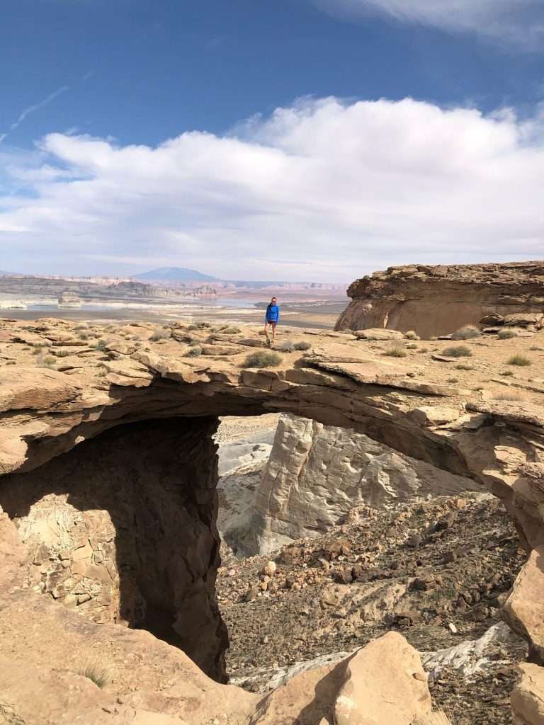 person in blue standing on top of rock bridge