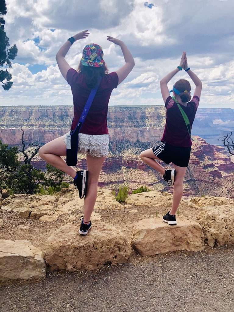 two girls doing tree pose on canyon overlook