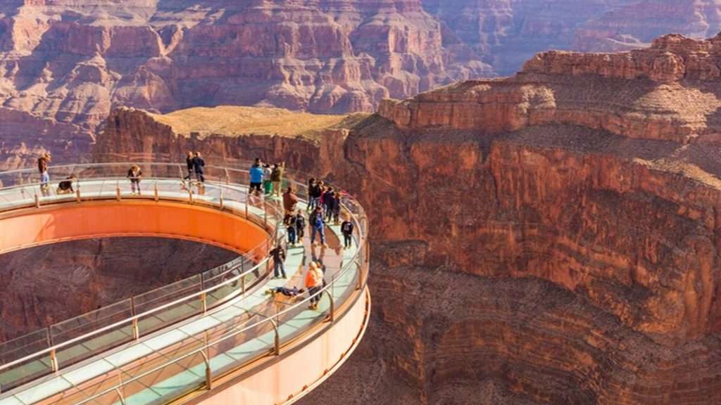 Visitors walk along the Grand Canyon Skywalk, a glass bridge extending over the canyon, offering stunning views of the rugged landscape.
